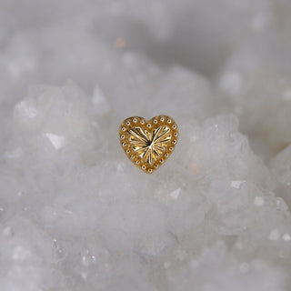 Gold heart-shaped jewelry piece on a crystal background junipurr lara textured laser cut heart with milgrain beaded outline push fit threadless