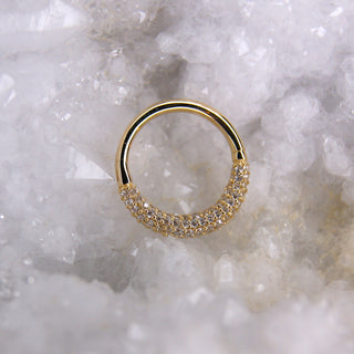 Gold ring with embedded stones on a textured white background junipurr jewellery opulence pave ring hinge clicker with 100 cz cubic zirconia